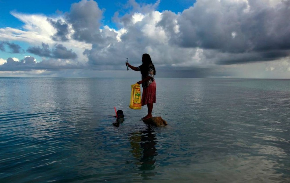 Binata Pinata stands on top of a rock holding a fish her husband Kaibakia just caught off Bikeman islet, located off South Tarawa in the central Pacific island nation of Kiribati, May 25, 2013. REUTERS/David Gray (KIRIBATI